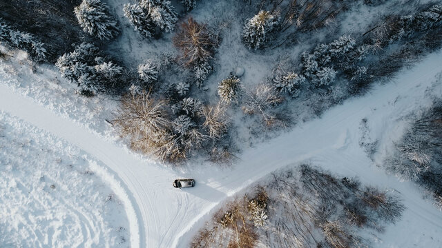 drone image. aerial view of forest area in winter with snowy trees. Three to four roads with car in the middle