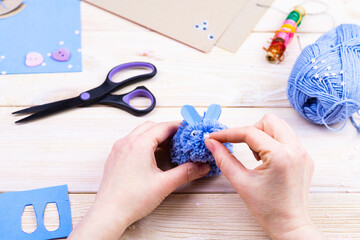How to make a bunny from pom-poms for Easter decor. Children's art project. DIY concept. Hands make a blue Easter bunny out of a pompom. Step by step photo instruction