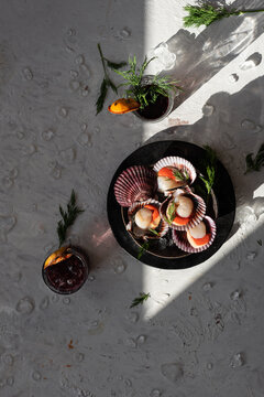 Top view of tasty oriental dish made of clams with herbs served on table with glasses of refreshing cocktails garnished with dried oranges