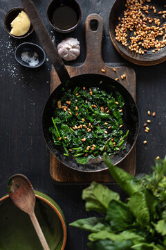 From above of tasty Catalan spinach with pine nuts in frying pan served on table in kitchen