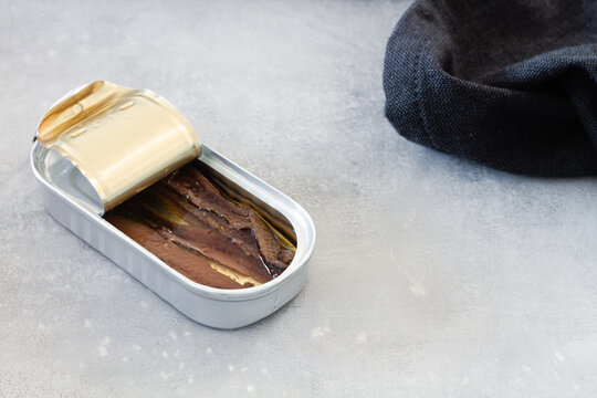 High angle of open metal can with fish conserves placed on table during food preparation