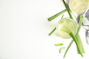 Fresh aloe drink and leaves on white table, flat lay. Space for text