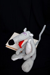 Soft toy of  gray rat sits on black background