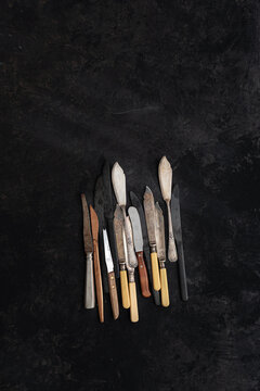 From above of collection of vintage knives placed on black background in studio