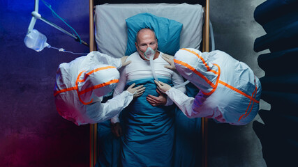 Top view of doctors and covid-19 patient with oxygen mask in bed in hospital, coronavirus concept.