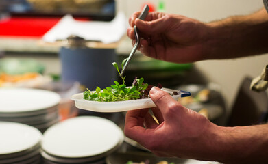 Chef preparando ensalada de diseño en cocina moderna e intuitiva