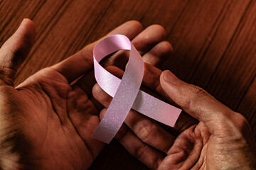 Pink ribbon on hands. Breast cancer awareness ribbon.