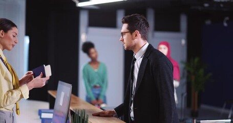 Airport worker woman servicing caucasian young businessman checking ID information and travel ticket on registration counter.