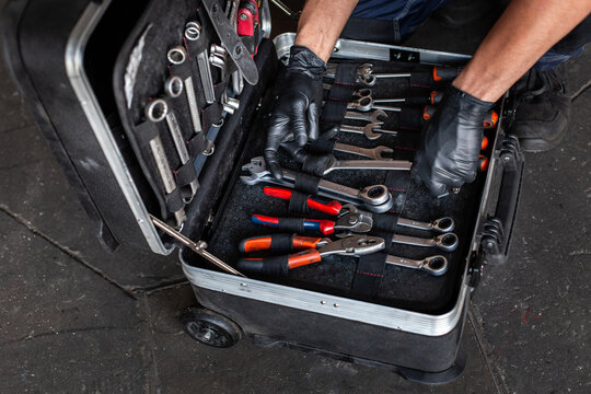 From above unrecognizable male technician picking screwdriver bits from tool box while working in garage