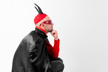Caucasian male model in halloween black red costume and sunglasses with hat and horns posing over...