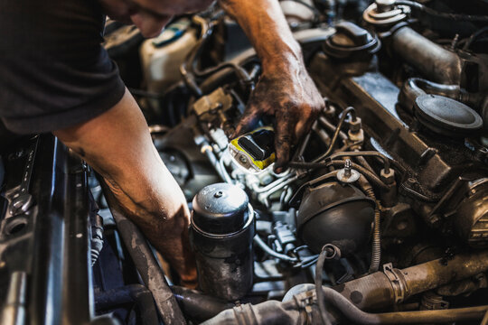 From above crop male mechanic illuminating engine with flashlight and checking motor of vehicle during work in garage