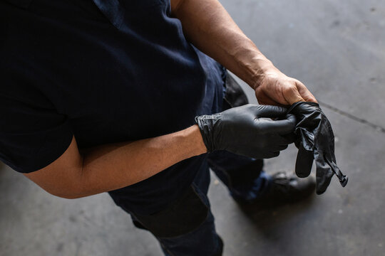 From above anonymous male employee putting on latex gloves during work in garage