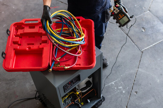 Crop man with modern voltage tester selecting cables while fixing machine in workshop