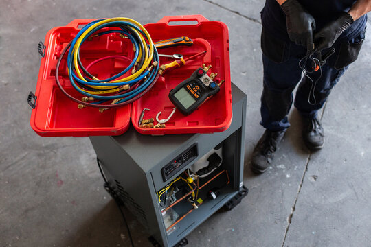 Crop man with modern voltage tester selecting cables while fixing machine in workshop