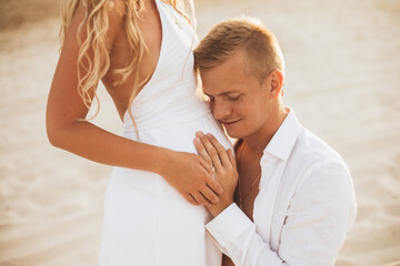 Fototapeta premium A man kisses his wife's pregnant belly.