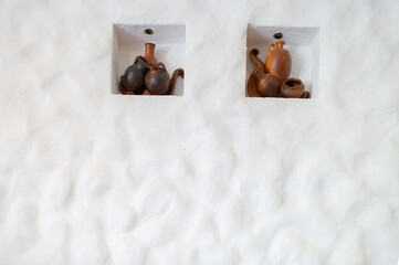 White wall decorated with hanging clay jugs