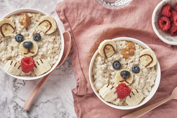 Oatmeal porridge bear with banana and berries, fun food art idea for kids food top view
