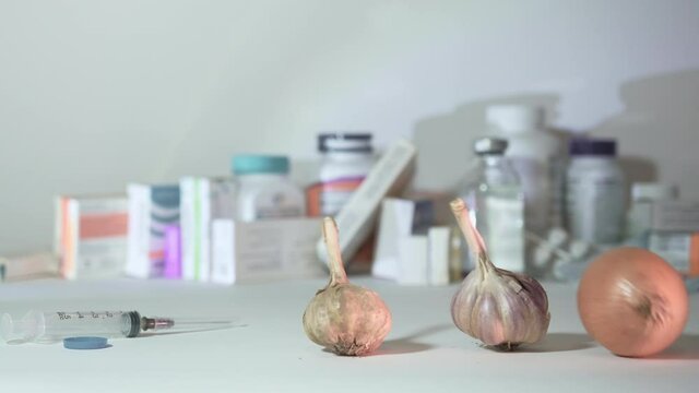 Man hand moves away the syringe with the vaccine and puts the garlic and onion. The concept of natural organic products and alternative medicine
