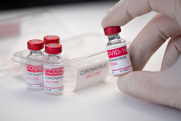 Closeup doctor hand holding a glass bottle of coronavirus vaccine. Concept of coronavirus vaccination. Macro
