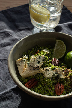 From above bowl with broccoli salad with couscous placed on dark fabric napkin