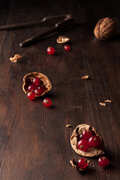 Top view still life composition with ripe red pomegranate seeds arranged in walnut shells on dark wooden background