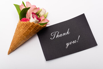 top view of flowers in waffle cone near card with thank you lettering on white