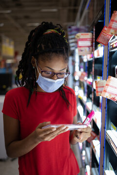 Afro latina young woman wearing a face mask shopping make up products