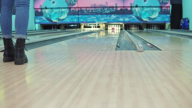 Girl throws a bowling ball on the track and knocks down pins