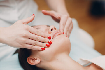 Beautiful young woman getting face treatment massage at beauty spa salon.