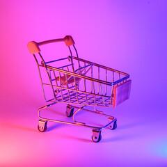 Shoping trolley with in trendy neon light. Gradient pink-blue glow. Concept art. Retro 80s. Minimalism shopping concept. Toy shopping trolley, neon