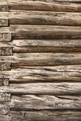 the texture of the wall of an old log house made of cylindrical logs without nails of a wooden house of a hut.