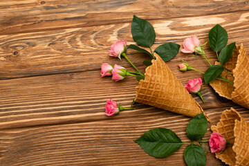 top view of pink flowers in waffle cones on wooden surface