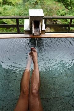 Legs and feet of caucasian female traveler enjoying a thermal waters bath in Japanese onsen, view from above