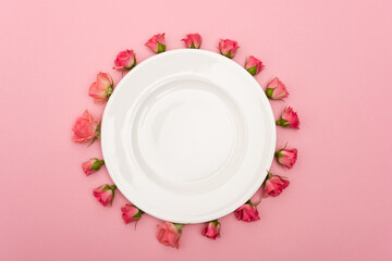 flat lay with white plate and tea roses isolated on pink