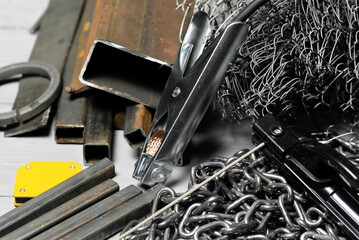 Welding close up concept background. Welding machine terminals and metal pieces on the workbench.