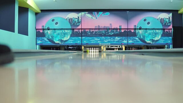 Close-up shot of a bowling ball on the track. The ball rolls along the track and knocks down the pins