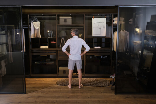 Stock photo of middle aged man choosing clothes for the day in his big dressing room.