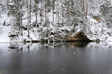 In the middle of the forest is a cliff with a reservoir of water pei those white and fluffy in winter form a reflection in the calm water