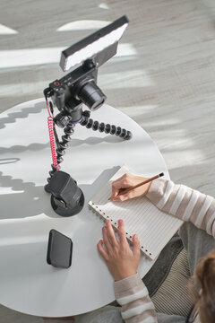 From above cropped unrecognized youtuber boy using camera and tripod at home for his video.