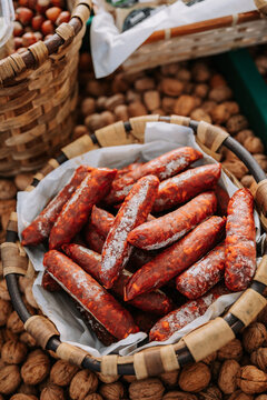 From above of whicker basket with yummy appetizing chorizo sausages placed among containers with nuts on local agricultural market