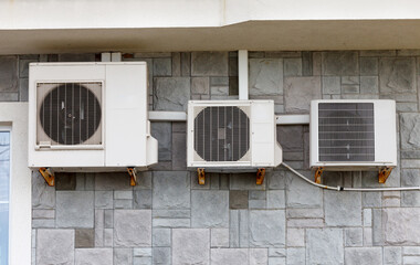 Three air conditioners of different sizes on the facade of the building.