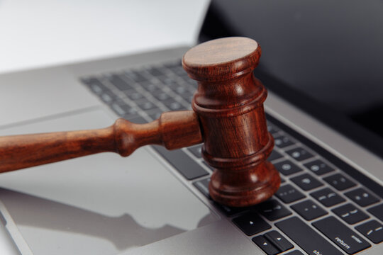 Judge's wooden gavel on laptop's keyboard.