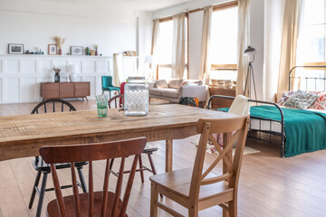 Vintage studio apartment interior in light colors in old style. huge room with large windows with a living room area and a bedroom area. direct sunlight inside.