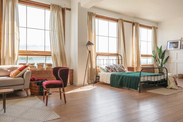 Vintage studio apartment interior in light colors in old style. huge room with large windows with a living room area and a bedroom area. direct sunlight inside.