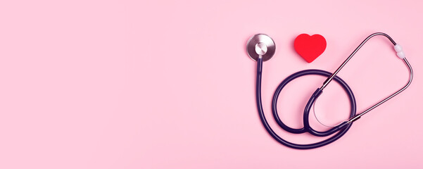World heart day banner background. Heart as a symbol of health, treatment, charity, donation and cardiology on a pink background with a medical statoscope.