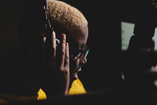 Side view of african American female radio host working in dark broadcast studio and speaking in microphone