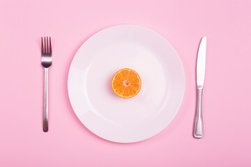 Orange on an empty white plate on a pink background. Food minimal creative art