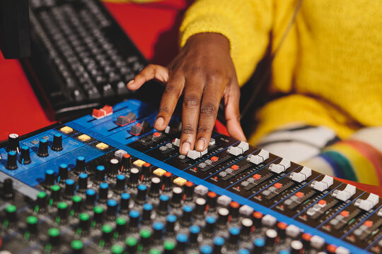 From above of unrecognizable ethnic female radio host using mixing consolel while working in broadcast studio