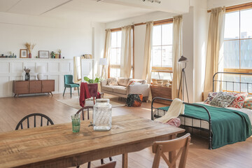 Vintage studio apartment interior in light colors in old style. huge room with large windows with a living room area and a bedroom area. direct sunlight inside.