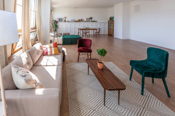 Vintage studio apartment interior in light colors in old style. huge room with large windows with a living room area and a bedroom area. direct sunlight inside.